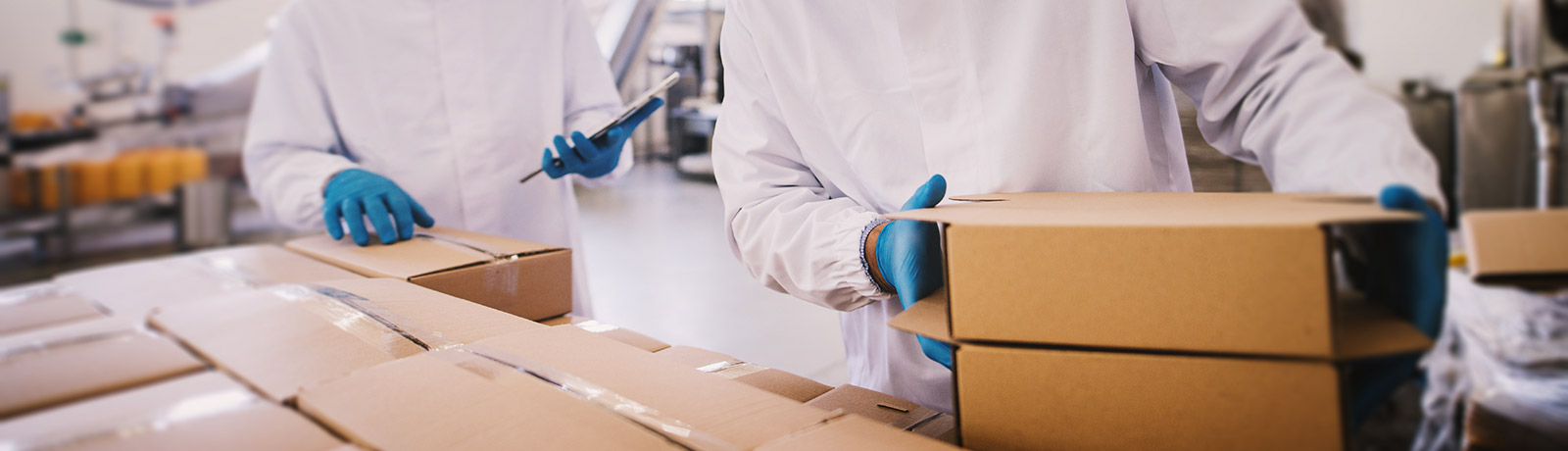 two male colleagues i sterile clothes preparing boxes with products for transport
