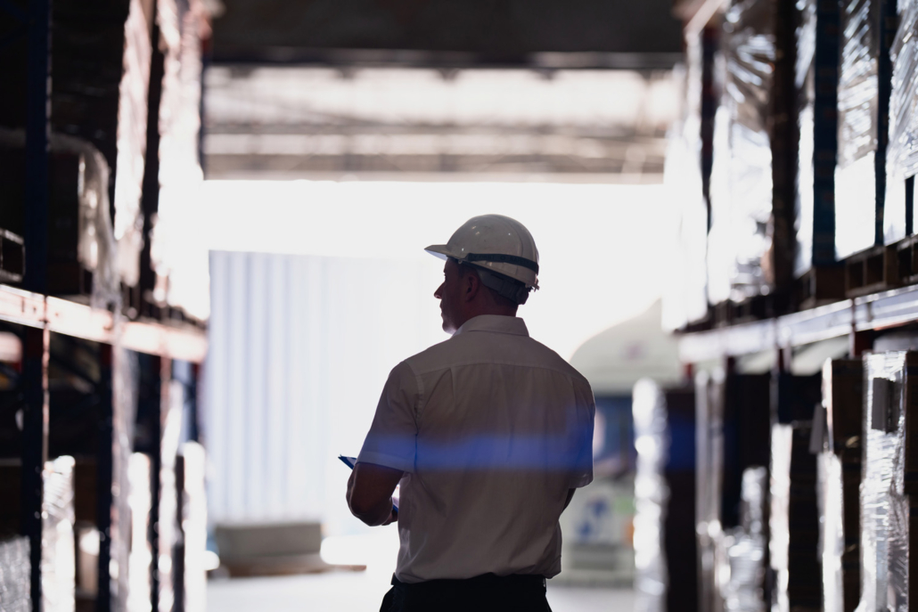 silhouette of a logistics worker with a hardhat walking through a warehouse