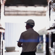 silhouette of a logistics worker with a hardhat walking through a warehouse